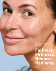 Close-up of a smiling woman with clear skin and freckles showing skincare results
