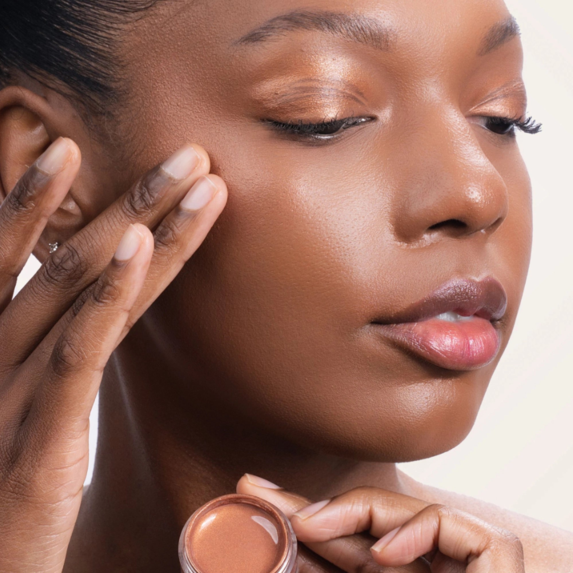 Model applying Bouncy Mousse Multi-Use Pigment product shade Bronze Bliss.