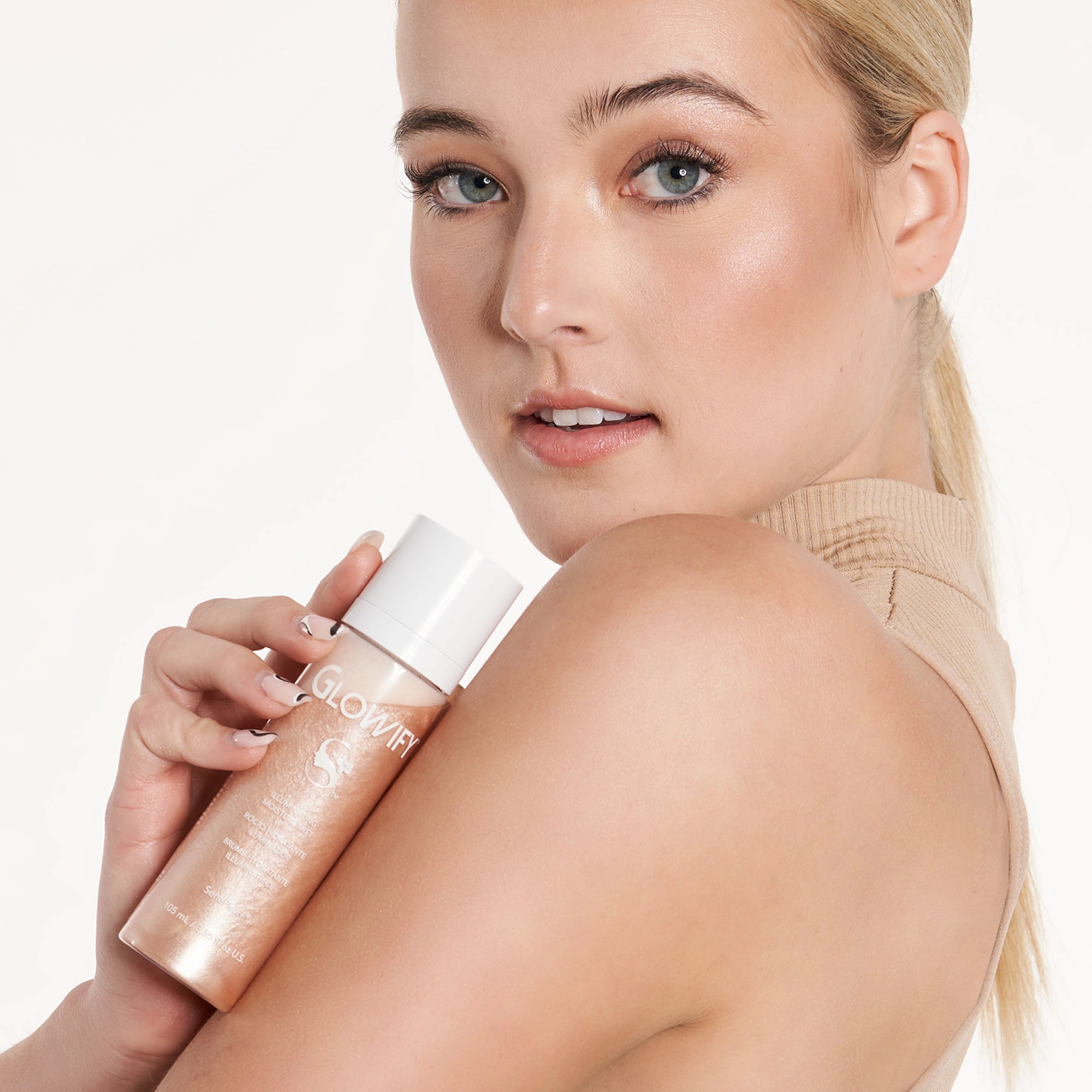 Model holding Illuminating Moisture Mist product shade Champagne.