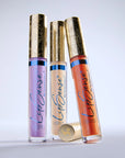 Three LipSense Prismatic gloss tubes with ornate gold caps standing upright.